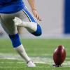A player running up to kick a football for kickoff
