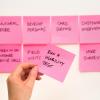 Person taking a sticky note with testing activities on it off a backlog wall