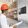 Employee in a warehouse looking at a dashboard on the wall